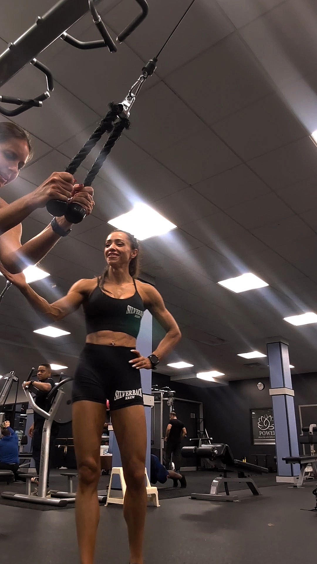 Lisa coaching a client through a lat pulldown at the gym